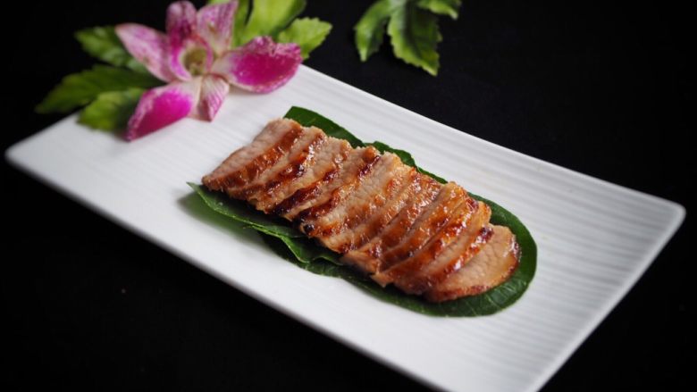 炭烧猪颈肉,上桌,配绿色菜叶和兰花 摆盘。