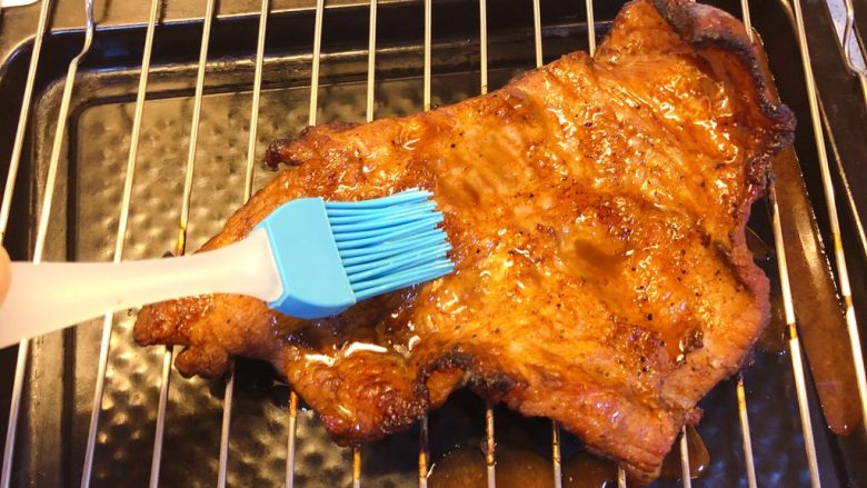 炭烧猪颈肉,15分钟后取出,双面抹上一层蜂蜜。
