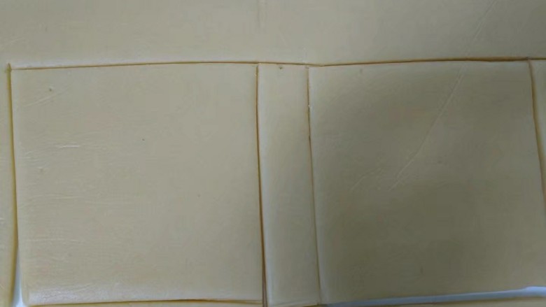 糖霜饼干,操作台铺上一张大油纸,将冷藏好的面团放在上面,盖上保鲜膜用擀面杖擀成3mm厚的面皮。(油纸小的话分两次擀)撕去保鲜膜,放上白纸切割出正方形。(这里我只切割6个正方形)