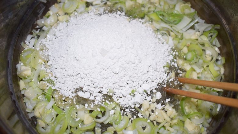 河南小吃——蒸素焖子,粉条煮10分钟即可关火。把葱、蒜和淀粉一块放进去,立即搅拌使葱、蒜、淀粉和粉条均匀混合。