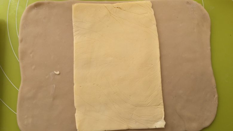 起酥小面包,冰箱取出冷冻的面片跟黄油,用剪刀将包裹黄油的保鲜袋裁开,将黄油片铺在面片中间