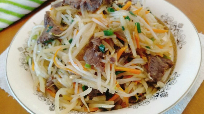 牛肉鲜虾薄饼卷,三匙油下锅,香葱爆香,将牛肉放进去爆炒,捞出备用,将胡萝卜土豆丝绿豆芽加两匙水放入焖6分钟,差不多好了,将牛肉混进去,加适量盐即可出锅