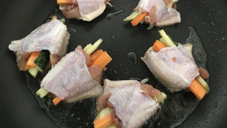 鸡翅换个花样做,时蔬酿鸡翅,把鸡翅码入,平滑那面先煎。