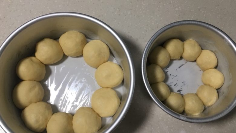 牛奶花环面包,面团排气整形后,按38克左右一个,19克左右一个, 平均分别分成10个圆球,一共20个,分别放入8寸、6寸圆形蛋糕模具里面,模具要提前刷油,刷油有利于脱模。