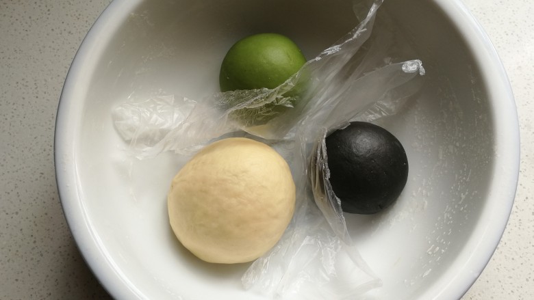 抹茶豹纹水立方吐司,把三种颜色的面团放入大碗中,用保鲜膜隔开再盖上保鲜膜发酵