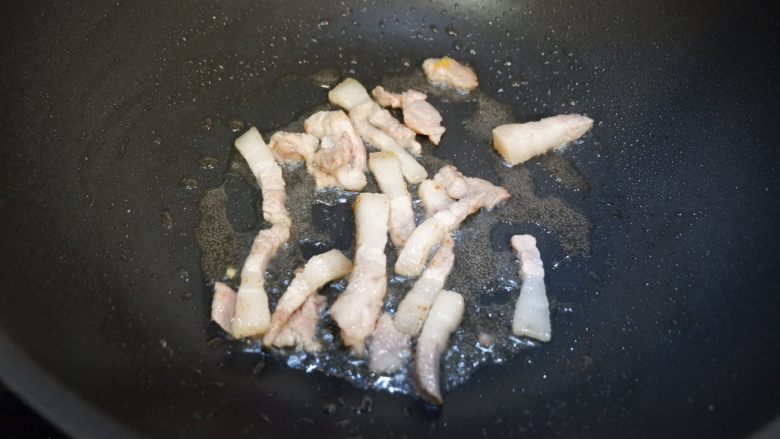 紫豆角烧土豆条,用中小火将五花肉煸炒至出油微焦