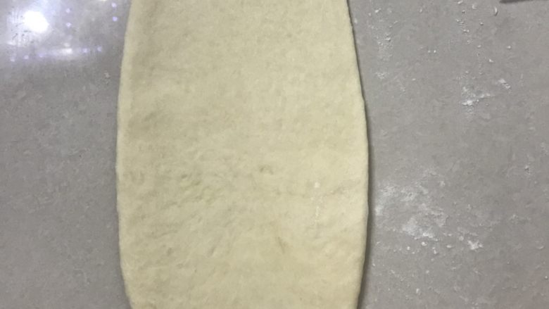 奶香椰蓉花式小餐包,取一面团先用手掌压一下,再用擀面杖擀成长舌形,边上的气泡用手拍掉