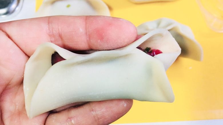 电饭锅版无油煎饺的包法,我们先用右手右边开始,靠里面的这个边短一点,外面的长一点,捏一下