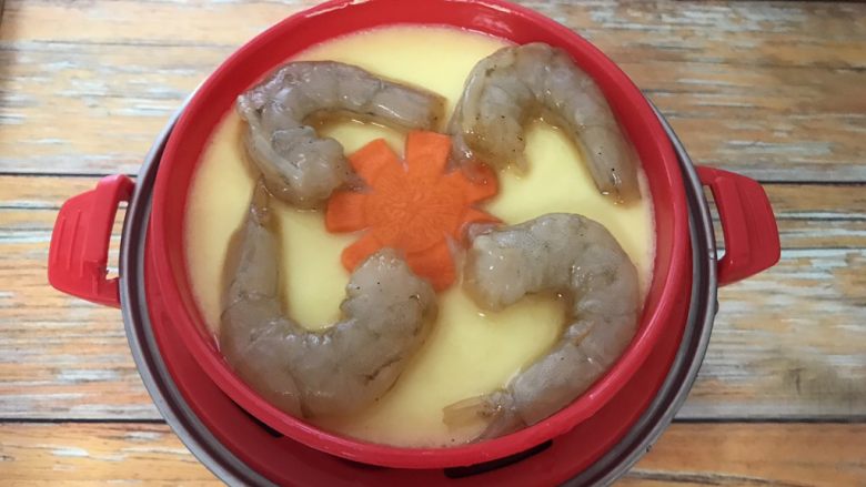 虾仁鸡蛋羹,蛋液表面基本凝固,打开透明盖,放入胡萝卜小花和腌制好的虾仁,继续盖上盖子蒸大约五分钟就熟了。