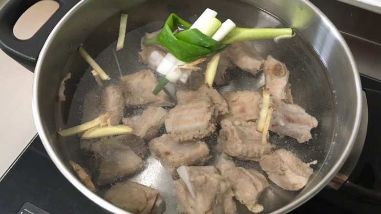 玉米胡萝卜排骨汤,另起锅,倒适量水,放入肋排、葱段、姜丝,加1勺料酒、1匙盐,大火烧开,转中小火煮30分钟
