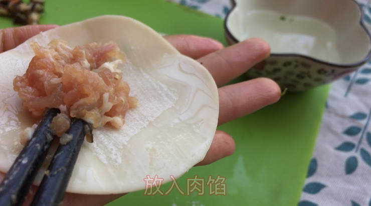 四喜福禄蒸饺(附猪肉馅调制过程),然后把买来的饺子皮四周抹上一咩咩水 比较好捏合 放入肉馅 不用放太多 因为一会还要做上面一层