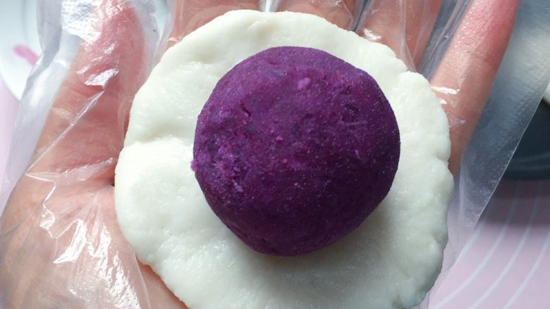 紫薯糯米饼,取一份糯米皮用手掌心按扁,放上一个紫薯泥