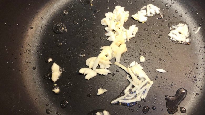 姜汁炒芥兰苗,热锅冷油,加入取姜汁之后剩下的姜丝炒香,倒入蒜茸,爆香姜丝和蒜片。