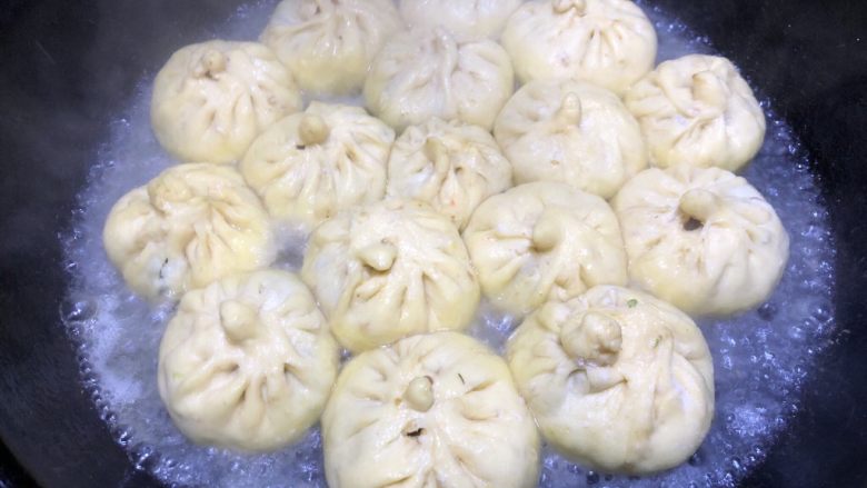 豆角猪肉生煎包,大约煎3分钟,包子底部有了脆皮之后倒入半碗水,水刚好没过包子底就可以,然后盖上锅盖转小火继续煎