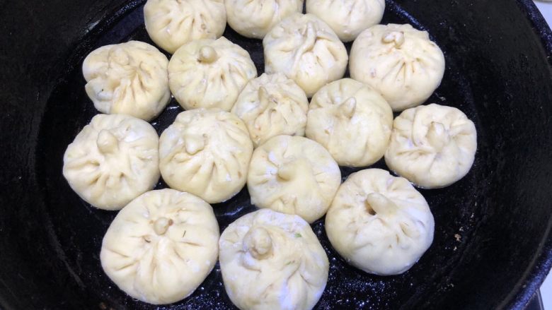 豆角猪肉生煎包,包完所有的包子后,取平底锅倒入油,油热之后将包子平均码好