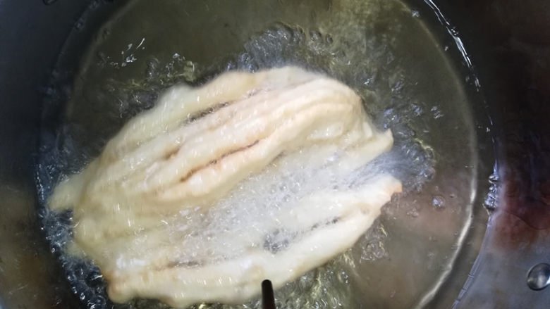 八股油条,锅中烧油,油温达到200度,提起八股油条胚的两头,放入油锅,立即用筷子左右拨动,让油条快速膨胀。炸至表面金黄就可以了。