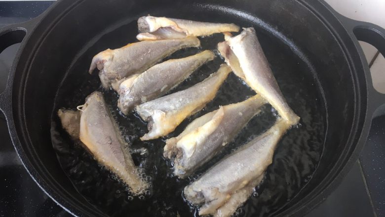 铁锅版红烧小黄花鱼,锅里放适量的油,油5、6成热时拎着鱼尾轻轻的贴着油面放到锅里。