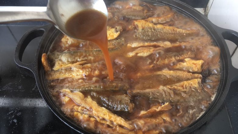铁锅版红烧小黄花鱼,炖鱼时可用双手端住锅把晃动锅,避免粘锅。另外用勺舀起汤汁浇在鱼上,反复几次,为了使锅里上边的鱼很好入味。