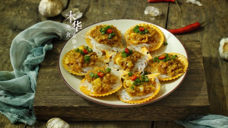 蒜蓉粉丝蒸扇贝,最后装饰上葱花喝红椒粒,每只扇贝淋上少量热油。就完成啦。