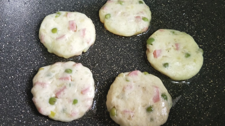 火腿豌豆土豆饼,锅加热,加入少量食用盐,把土豆饼放进锅中煎