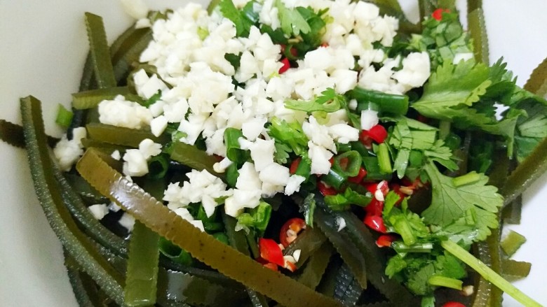 夏日必备凉菜,绝对颠覆你的味蕾——凉拌海带丝,蒜末、香菜末、小葱末、辣椒末放在海带丝上面。