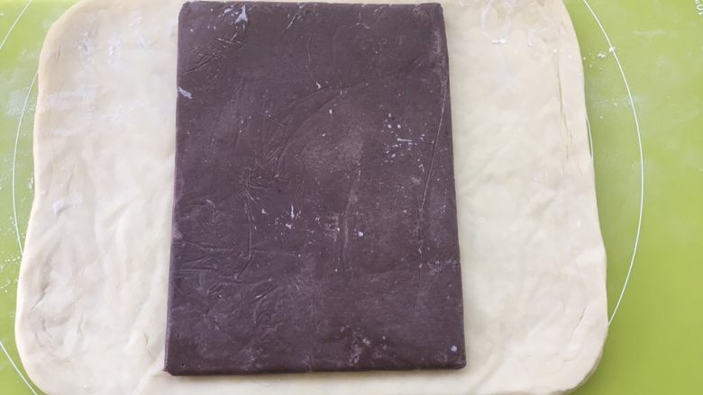 大理石金砖,冰箱取出冷冻的面片跟豆沙片,用剪刀裁开豆沙保鲜袋,将豆沙片铺在面片中间