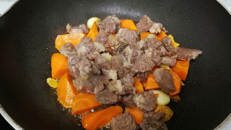 红萝卜焖牛腩,从高压锅里捞出牛腩,去掉所有香料,倒入炒锅,与红萝卜一起翻炒片刻。