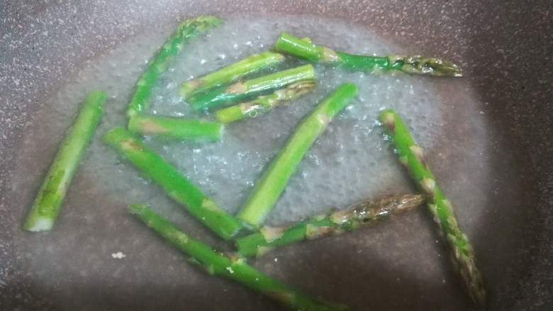 香煎培根芦笋卷,锅里放入少量的水,为了保持芦笋的翠绿和口感脆爽,水里加半勺盐和几滴油,水沸后放入芦笋 ,焯烫半分钟左右。