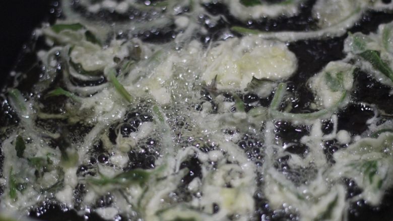 香椿的三种吃法,把吸干水分的香椿放到面糊碗里裹上面糊,油温烧至八成热下油锅炸定型,颜色变得微黄后及时翻面