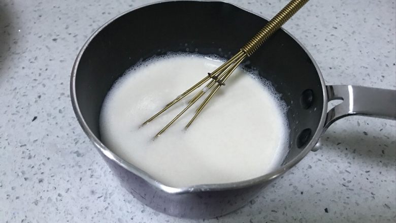 棋格慕斯蛋糕,吉利丁片泡软后,攥干水分,放入牛奶中,倒入奶锅中,小火加热至吉利丁片完全融化,室温放到温热。