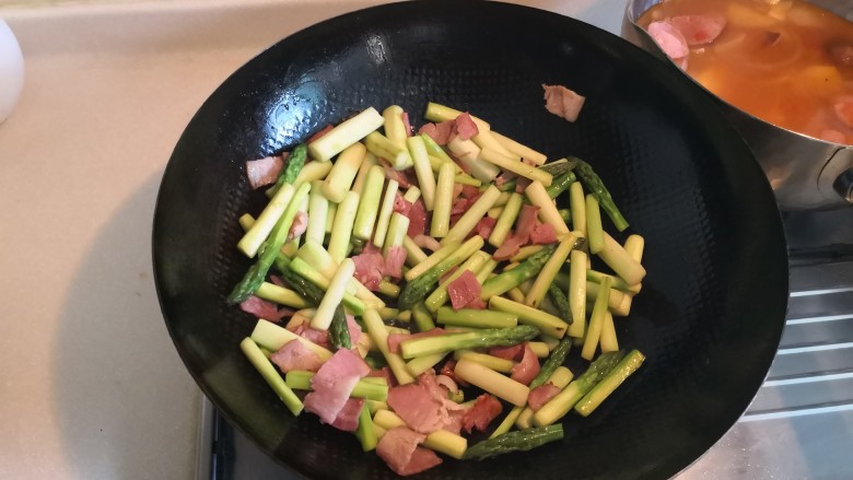 芦笋炒培根,加入芦笋继续翻炒，加入适量的盐。