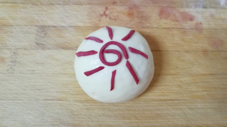 阳光大馒头,再把红色的细面条切成一截一截的,粘在周围,形成太阳的光芒,一个阳光大馒头就做好了。