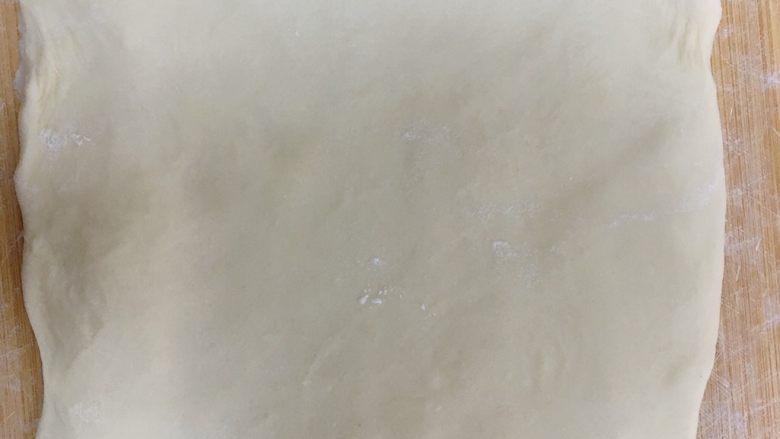 不用开酥酥的掉渣的黑芝麻蛋黄酥,静置好的水油皮擀成长方形,将油酥取出铺在水油皮上包起来,轻轻的擀成长方形,来回对折一次,再擀成长方形