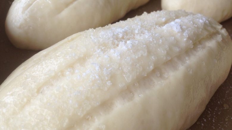 蛋清奶香面包,面包坯发酵好后取出,割三道口子,在表面喷点水,撒上粗砂糖