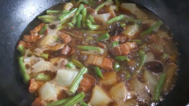 东北五花肉烩菜,中火炖至土豆绵软,豆角软烂即可。