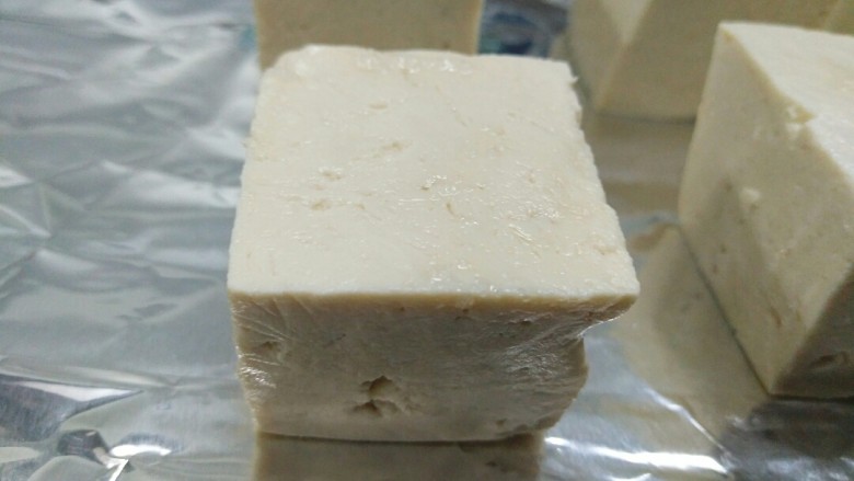 豆腐新花样,你不确定来一份吗?,豆腐捞起晾干或擦干水分,摆放在烤盘上,烤盘上最好垫上锡纸,入预热210度烤箱烤10分