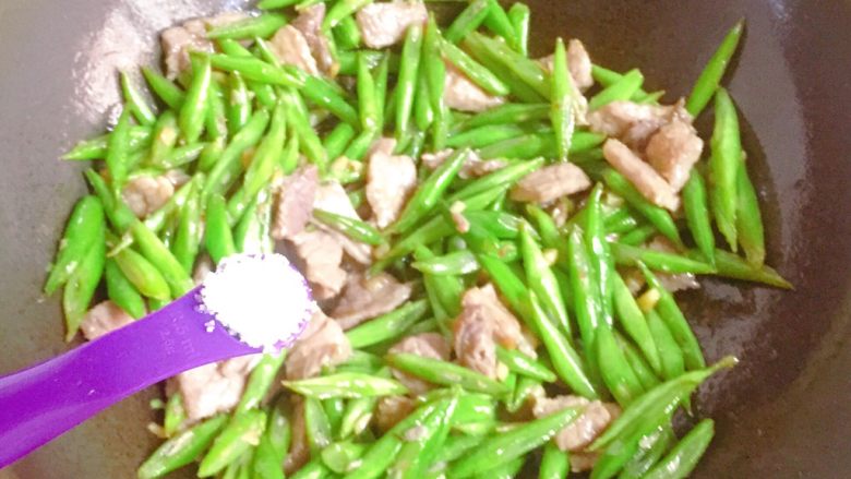 家常小炒四季豆,倒入四季豆,接着加入适量盐调味