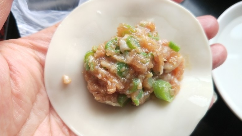 豆角猪肉馅饺子,手上蘸清水,沿饺子皮抹一圈,放适量的饺子馅。