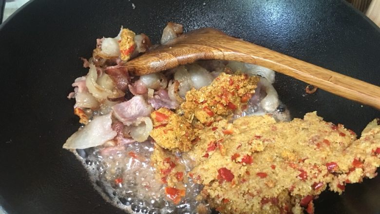 渣海椒腊肉,腊肉铲在边上,倒入渣海椒在油里迅速翻炒,这里动作要快,渣海椒很容易成一坨、糊了锅底。让渣海椒炒进油后,再混合腊肉一起翻炒均匀。
