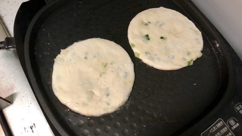 发面葱油饼,把面饼房进电饼铛,盖上盖子,用“大饼”模式开始烙制。