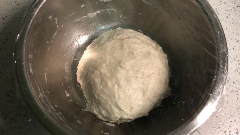 发面葱油饼,然后把面和成团,不需要揉的很光滑,揉至均匀没有干粉即可,粘手是正常的,因为含水量多。然后盖上保鲜膜进行基础发酵。