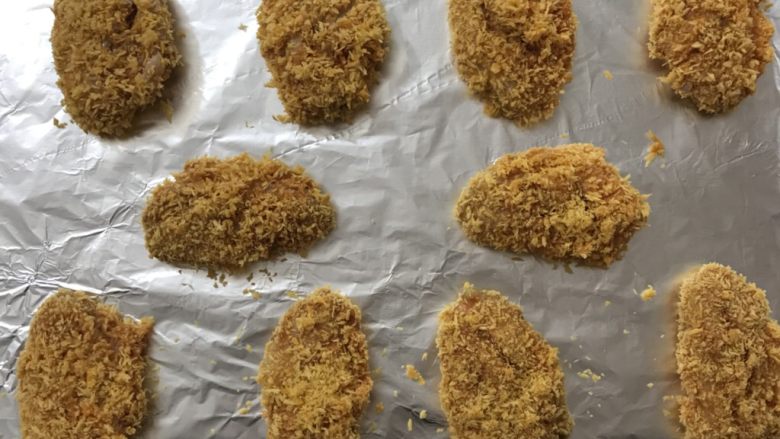 面包糠烤鸡翅,把鸡翅排放在铺了锡纸的烤盘上,放入预热好的烤箱,210度,15分钟。