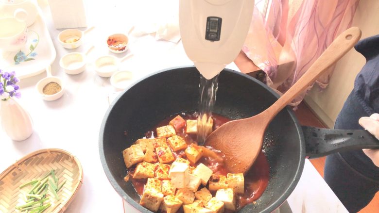 麻婆豆腐,倒入没过豆腐一半的高汤或清水,使用推锅铲的方式。