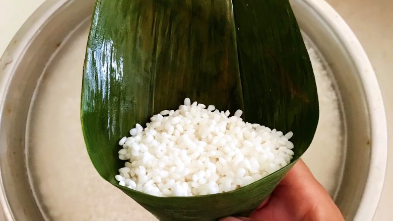 北方传统粽子,在粽叶里面加入浸泡好的糯米,糯米加到粽叶的2/3处即可,再加入清水,让米粒下沉,减少空隙