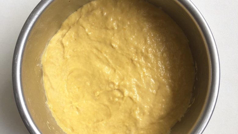 南瓜发糕,倒入面糊，抹平表面。可以在手背沾少许油来抹，这样可以防粘