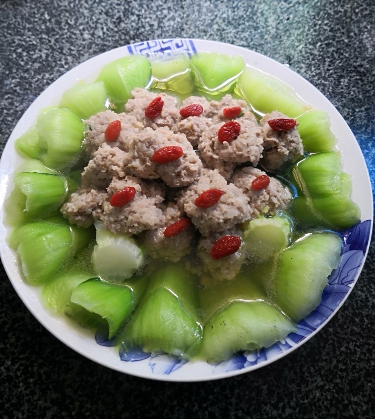 江南美景,漏勺捞出丸子放在青江菜上面摆好盘,丸子上点缀用开水泡软的<a style='color:red;display:inline-block;' href='/shicai/ 673'>枸杞</a>。再把煮丸子的汤倒适量到盘中。江南美呈现在眼前。👌(这道菜煮丸子时余下来的汤,加点葱花,直接当汤喝,清甜沁人心脾。)