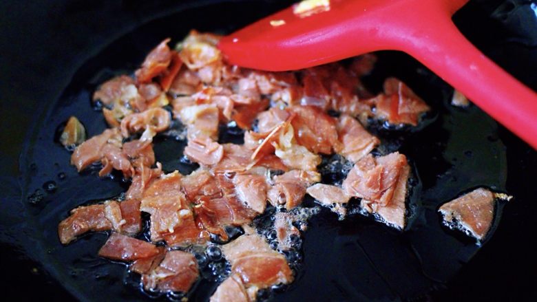 培根鸭蛋杂蔬炒饭,这个时候再重新另起锅烧热后,加入剩下的30克花生油烧热后,把切好的培根小丁放到锅里进行翻炒片刻;