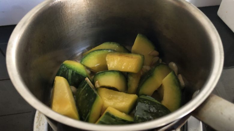 小奶锅煮日式南瓜,颠一下锅,再干煎一分钟。开盖,南瓜块边缘略焦即可进行后续步骤。