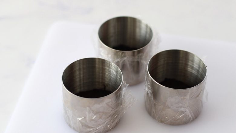 蓝莓酸奶慕斯,提前将模具底部用保鲜膜包起来,将黄油奥利奥混合物倒进模具,用擀面杖压实,放冰箱冷藏