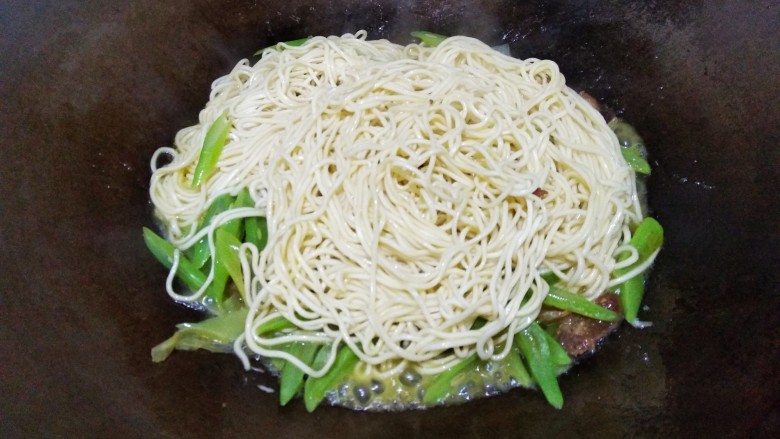豆角焖面,面条吸收汤汁,用筷子将面条翻动。
